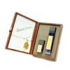 Perfumes en estuche marrón, envases rectangulares, líquido azul, tapa negra, etiqueta dorada. Santa Cistina en tarjeta blanca.