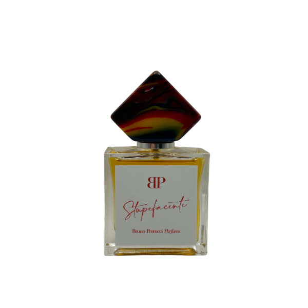 Perfume elegante, cuadrado, líquido ámbar, etiqueta gris y Stupefacente en letras rojas.